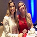Two UTMB pathology residents seated together at a conference table during a formal event, with place settings and soft lighting, attending a professional networking or awards gathering.