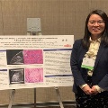 UTMB pathology resident Yuan presenting research at a medical conference poster session, discussing findings with attendees in an academic setting.