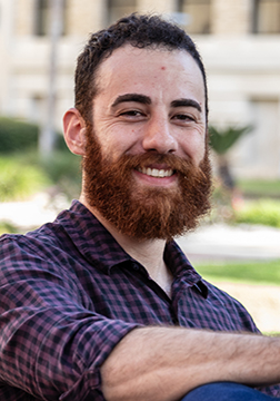 Picture of a man smiling outside with a building in the background