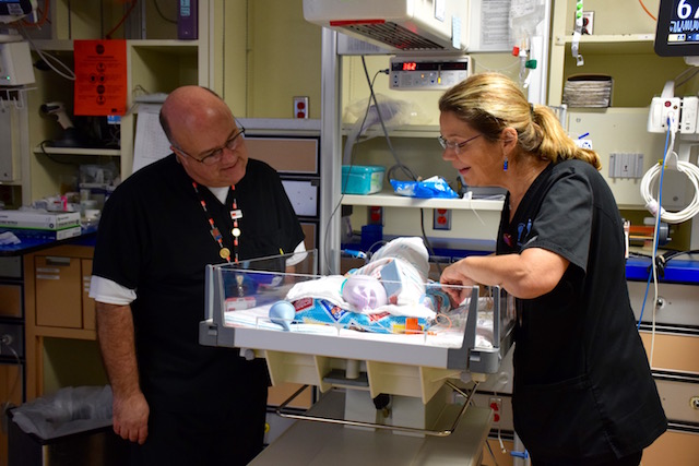 David Marshall and nurse Betsy Petersen check on a baby in the neonatal ICU.