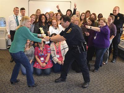 Connie Barton and Lt. David DeOre “fight” over the first-place trophy. Walktober