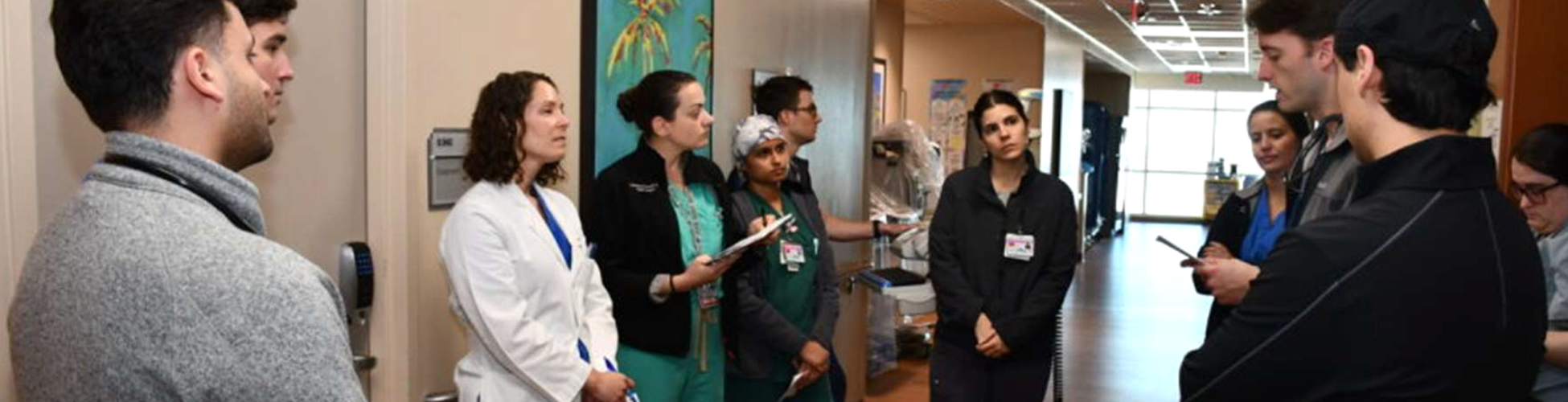 A group of anesthesiology critical care fellows and faculty participate in bedside rounds in a hospital unit at UTMB.