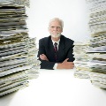 Seated man surrounded by stacks of documents