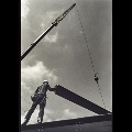Construction worker guiding girder hanging from crane