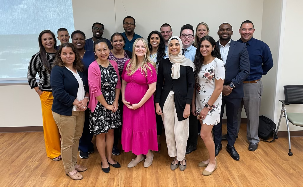 Group portrait of UTMB Department of Pharmacy residents standing indoors in a modern building.