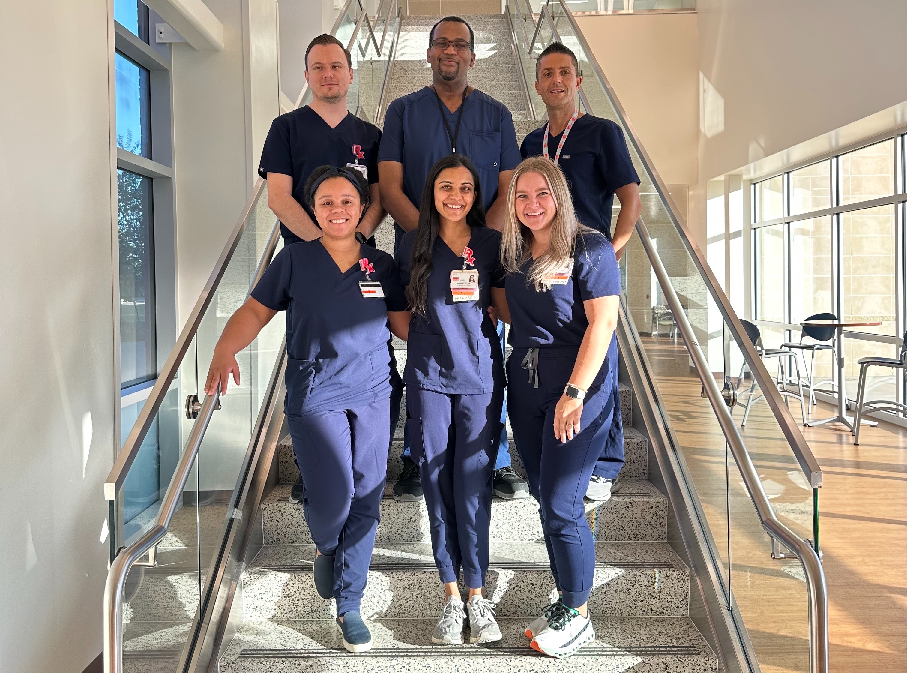 Group portrait of the PGY2 Ambulatory Care Pharmacy Residency Program team standing on an indoor staircase in a modern building.