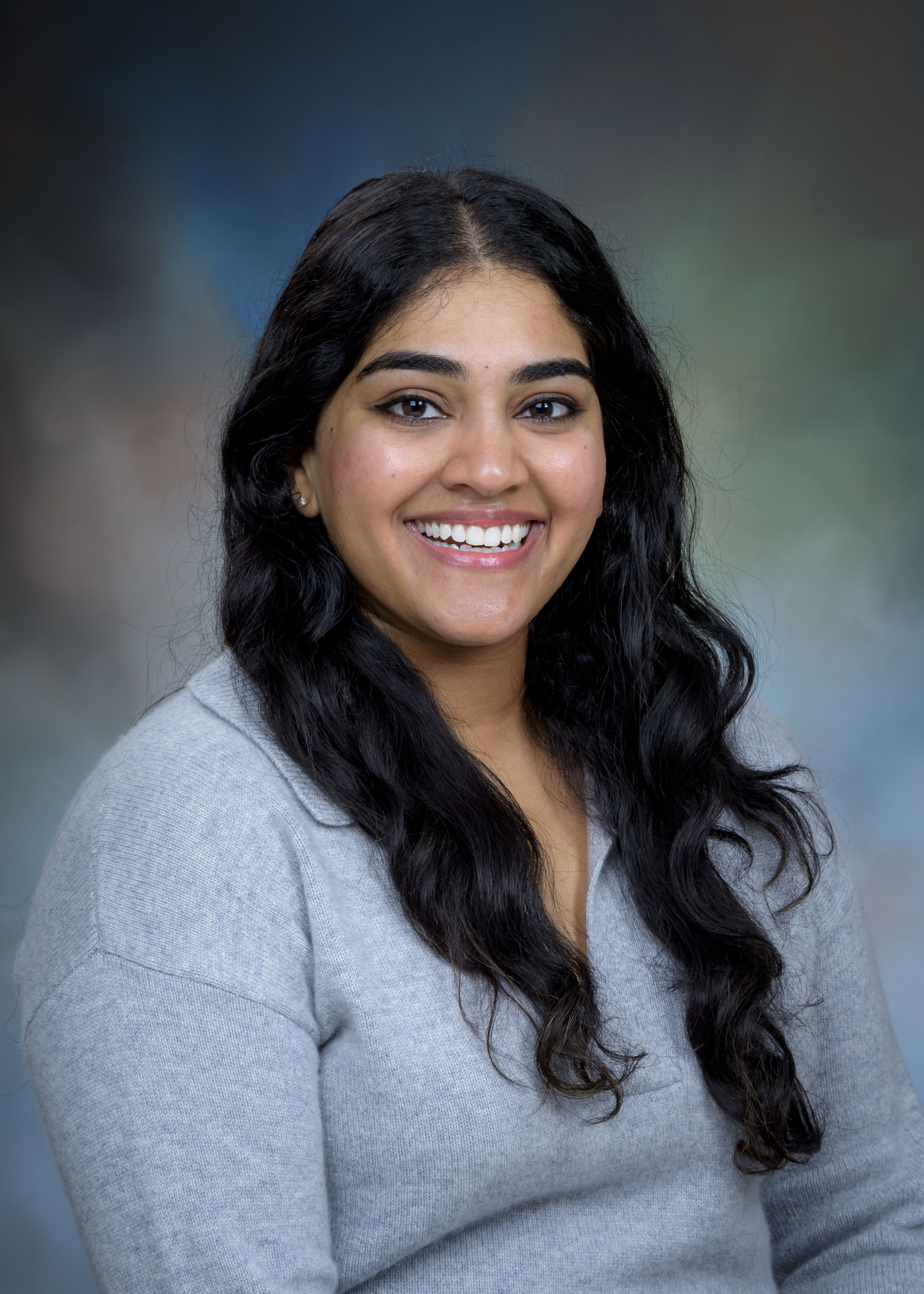 Studio portrait of a pharmacy preceptor wearing a light gray top, photographed against a softly blended neutral background.