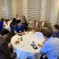 Attendees seated around a round table labeled “Team #5” eat and converse during the Alpha Omega Alpha Texas Chapter UTMB 2022 Fall Mixer, with plates of food, drinks, and notepaper visible on the table.