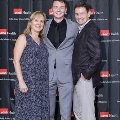Three individuals pose together at the Alpha Omega Alpha 2023 Induction Ceremony at UTMB in front of a UTMB Health and John Sealy School of Medicine branded backdrop, with one wearing a gray suit.