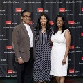 Three individuals stand together at the Alpha Omega Alpha 2023 Induction Ceremony at UTMB, posing in front of a UTMB Health and John Sealy School of Medicine branded backdrop.