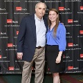 Two individuals stand together in front of a UTMB Health and John Sealy School of Medicine branded backdrop at the Alpha Omega Alpha 2023 Induction Ceremony, posing for a portrait.