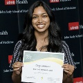 An individual holds a certificate reading “Congratulations Snehan Jayawickrama” at the Alpha Omega Alpha 2023 Induction Ceremony at UTMB, standing in front of a UTMB Health and John Sealy School of Medicine backdrop.