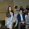 An individual walks down an aisle during the Alpha Omega Alpha 2023 Induction Ceremony at UTMB, with seated attendees visible on both sides in a ballroom setting.