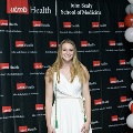 An individual stands centered between red, white, and gray balloon columns for a portrait at the Alpha Omega Alpha 2023 Induction Ceremony at UTMB, with a UTMB Health and John Sealy School of Medicine backdrop.