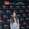 An individual stands centered between red, white, and gray balloon columns for a portrait at the Alpha Omega Alpha 2023 Induction Ceremony at UTMB, with a UTMB Health and John Sealy School of Medicine backdrop.