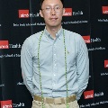 An individual stands for a formal portrait at the Alpha Omega Alpha 2023 Induction Ceremony at UTMB, wearing green honor cords in front of a UTMB Health and John Sealy School of Medicine logo backdrop.