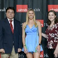 Three individuals stand together at the Alpha Omega Alpha 2023 Induction Ceremony at UTMB, posing in front of a UTMB Health and John Sealy School of Medicine logo backdrop, with one individual wearing green honor cords.