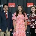 Three individuals stand together at the Alpha Omega Alpha 2023 Induction Ceremony at UTMB, posing in front of a UTMB Health and John Sealy School of Medicine logo backdrop.