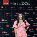 An individual stands centered between red, white, and gray balloon columns for a portrait at the Alpha Omega Alpha 2023 Induction Ceremony at UTMB, in front of a UTMB Health and John Sealy School of Medicine backdrop.