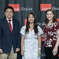 Three individuals pose together at the Alpha Omega Alpha 2023 Induction Ceremony at UTMB, standing in front of a UTMB Health and John Sealy School of Medicine logo backdrop.