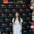 An individual poses at the Alpha Omega Alpha 2023 Induction Ceremony at UTMB, standing near red, white, and gray balloon decorations with a UTMB Health and John Sealy School of Medicine backdrop.