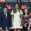 Three individuals stand together at the Alpha Omega Alpha 2023 Induction Ceremony at UTMB, posing in front of a UTMB Health and John Sealy School of Medicine branded backdrop.