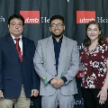 Three individuals pose together at the Alpha Omega Alpha 2023 Induction Ceremony at UTMB, standing in front of a UTMB Health and John Sealy School of Medicine backdrop.