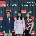 Three individuals stand together at the Alpha Omega Alpha 2023 Induction Ceremony at UTMB, posing in front of a UTMB Health and John Sealy School of Medicine logo backdrop.