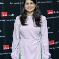 An individual poses for a portrait in front of a UTMB Health and John Sealy School of Medicine logo backdrop at the Alpha Omega Alpha 2023 Induction Ceremony.