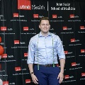 An individual stands in front of a UTMB Health and John Sealy School of Medicine branded backdrop, wearing honor cords during the Alpha Omega Alpha 2023 Induction Ceremony.