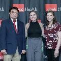 Three individuals pose together at the Alpha Omega Alpha 2023 Induction Ceremony at UTMB, standing in front of a UTMB Health and John Sealy School of Medicine branded backdrop.