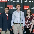 Three individuals pose together at the Alpha Omega Alpha 2023 Induction Ceremony at UTMB, standing before a UTMB Health and John Sealy School of Medicine logo backdrop.