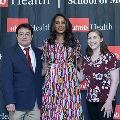 Three individuals stand together at the Alpha Omega Alpha 2023 Induction Ceremony at UTMB, posing in front of a UTMB Health and John Sealy School of Medicine branded backdrop.