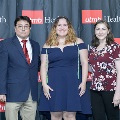 Three individuals pose together at the Alpha Omega Alpha 2023 Induction Ceremony at UTMB in front of a UTMB Health and John Sealy School of Medicine branded backdrop.