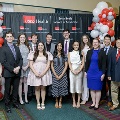 A group of individuals pose together at the Alpha Omega Alpha 2023 Induction Ceremony at UTMB, standing in front of a UTMB Health and John Sealy School of Medicine backdrop with balloon decorations to the side.