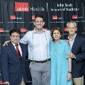Four individuals pose at the Alpha Omega Alpha 2023 Induction Ceremony at UTMB, framed by red, white, and gray balloon columns with a UTMB Health and John Sealy School of Medicine backdrop.
