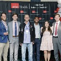 Six individuals pose together at the Alpha Omega Alpha 2023 Induction Ceremony at UTMB, standing between red, white, and gray balloon columns in front of a UTMB Health and John Sealy School of Medicine backdrop.