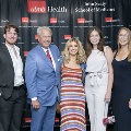 A group of five individuals pose together at the Alpha Omega Alpha 2023 Induction Ceremony at UTMB, framed by red, white, and gray balloon columns with a UTMB Health backdrop behind them.