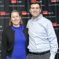 Two individuals stand side by side at the Alpha Omega Alpha 2023 Induction Ceremony at UTMB, posing in front of a UTMB Health and John Sealy School of Medicine logo backdrop.