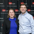 Two individuals stand together at the Alpha Omega Alpha 2023 Induction Ceremony at UTMB, posed in front of a UTMB Health and John Sealy School of Medicine branded backdrop.