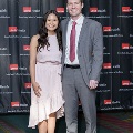 Two individuals stand side by side for a full-length portrait at the Alpha Omega Alpha 2023 Induction Ceremony at UTMB, in front of a UTMB Health and John Sealy School of Medicine logo backdrop.