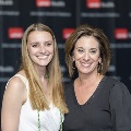 Two individuals stand side by side smiling at the Alpha Omega Alpha 2023 Induction Ceremony at UTMB, posed in front of a branded black backdrop with repeating logos.