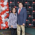 Two attendees pose together at the 2023 Alpha Omega Alpha Texas Chapter Fall Mixer at UTMB, standing in front of a black UTMB Health backdrop and a red, white, and gray balloon arrangement.
