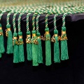 Close-up of green Alpha Omega Alpha honor cords with gold “AOA” charms and tassels arranged neatly along the edge of a black table at a UTMB Texas Alpha Chapter event.