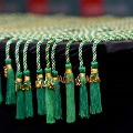 Close-up of green Alpha Omega Alpha honor cords with gold “AOA” charms and tassels arranged neatly along the edge of a black table at a UTMB Texas Alpha Chapter event.