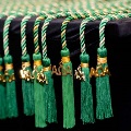 Close-up of green Alpha Omega Alpha honor cords with gold “AOA” charms and tassels arranged neatly along the edge of a black table at a UTMB Texas Alpha Chapter event.