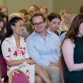 Attendees seated in red chairs, including two individuals in the foreground holding a program, during an Alpha Omega Alpha Texas Alpha Chapter event at UTMB.