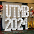 Illuminated “UTMB 2024” letters displayed with red, white, and gold balloon decorations in an indoor event setting for an Alpha Omega Alpha Texas Alpha Chapter celebration.