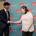 Two individuals shake hands in front of a UTMB Health backdrop during an Alpha Omega Alpha Texas Alpha Chapter recognition ceremony at UTMB.