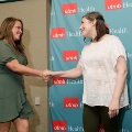 Two attendees shake hands in front of a UTMB Health backdrop during an Alpha Omega Alpha Texas Alpha Chapter recognition ceremony at UTMB.